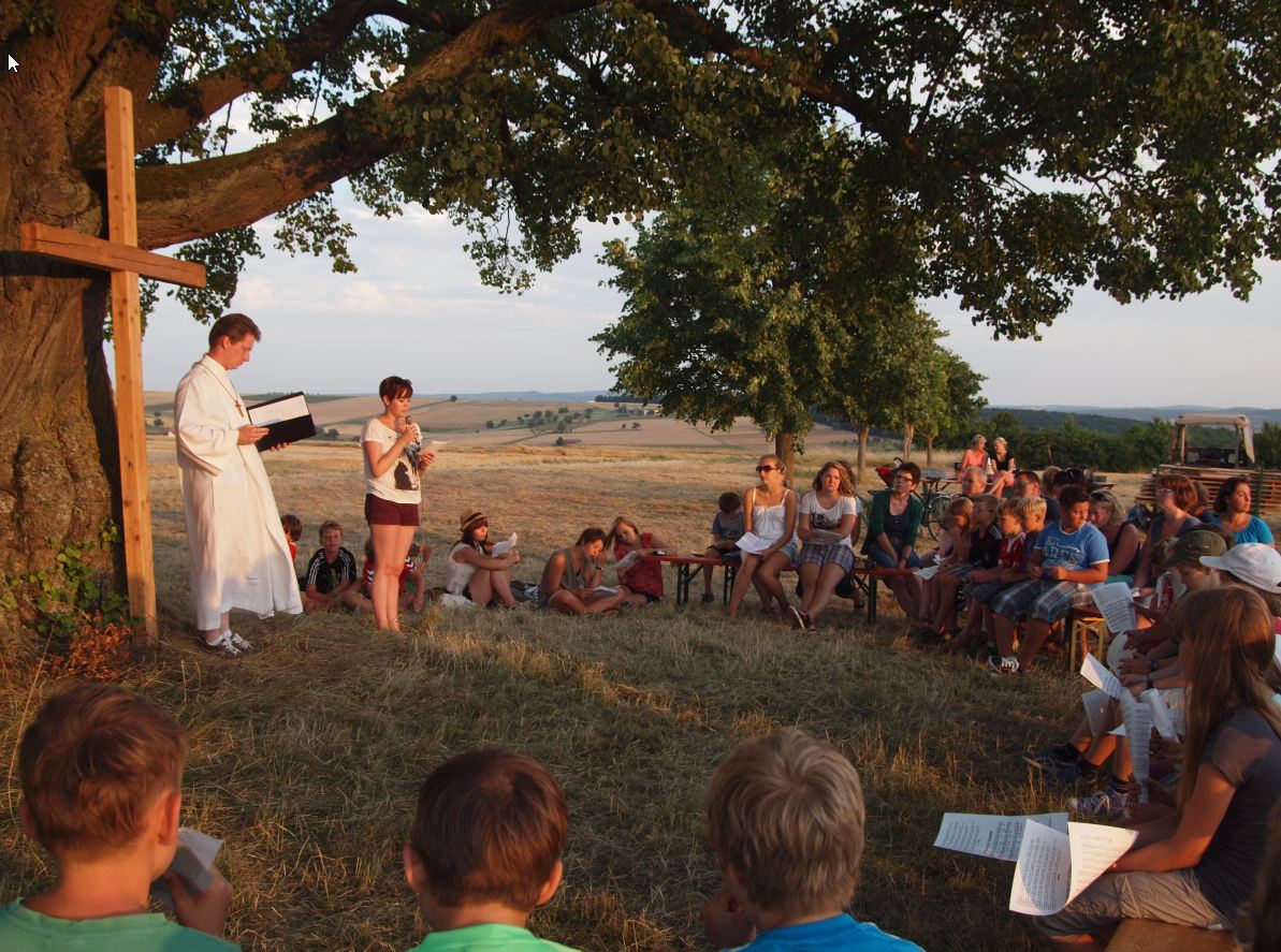 Unter einem Baum im Freien findet ein Gottesdienst statt.