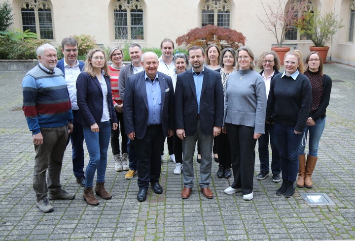 Christoph Gawronski ist aus der Abteilung Pastorale Entwicklung und Konzeption verabschiedet worden. Links von ihm Domkapitular Albin Krämer, Leiter der Hauptabteilung Seelsorge, rechts Abteilungsleiterin Christine Steger, umgeben von Kolleg:innen