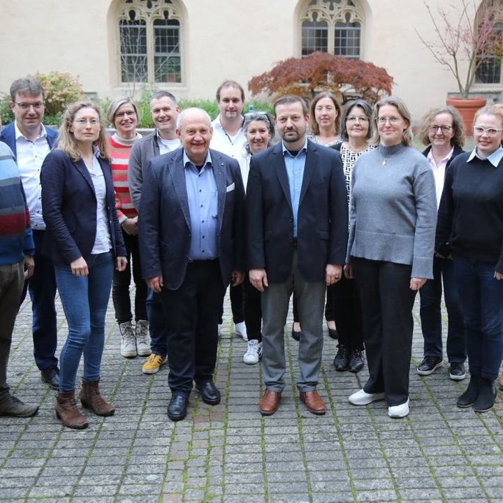 Christoph Gawronski ist aus der Abteilung Pastorale Entwicklung und Konzeption verabschiedet worden. Links von ihm Domkapitular Albin Krämer, Leiter der Hauptabteilung Seelsorge, rechts Abteilungsleiterin Christine Steger, umgeben von Kolleg:innen