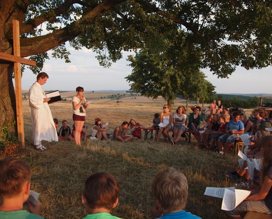 Unter einem Baum im Freien findet ein Gottesdienst statt.